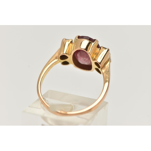 67 - A YELLOW METAL FIVE STONE RING, centering on an oval cut heavily fracture filled red corundum, in a ... 