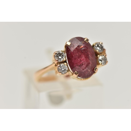 67 - A YELLOW METAL FIVE STONE RING, centering on an oval cut heavily fracture filled red corundum, in a ... 