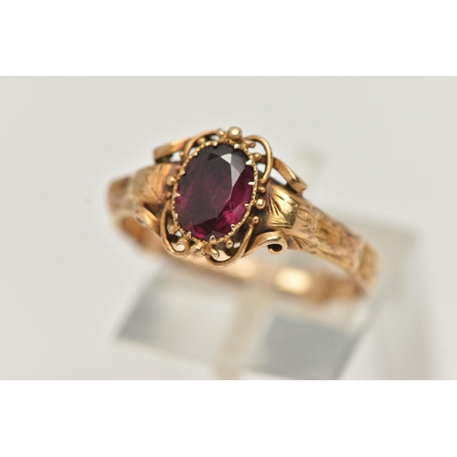 69 - A VICTORIAN YELLOW METAL GARNET RING, centering on an oval cut garnet, claw set, the reverse of the ... 