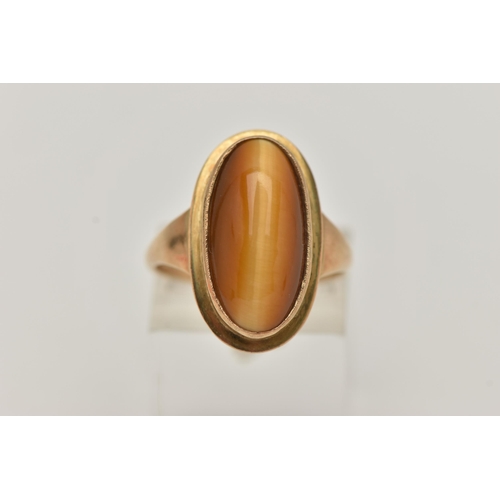 134 - A 9CT GOLD DRESS RING, an elongated oval cabochon tigers eye, collet set in yellow gold, leading on ... 