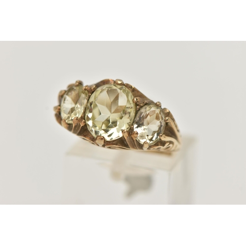 135 - A 9CT GOLD GEM SET RING, three light yellow oval cut quartz stones, prong set in yellow gold, scroll... 