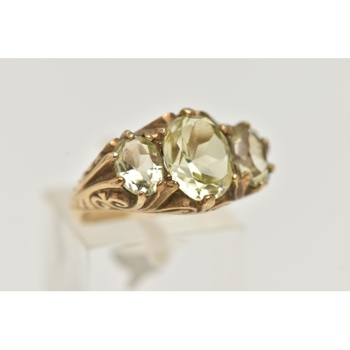 135 - A 9CT GOLD GEM SET RING, three light yellow oval cut quartz stones, prong set in yellow gold, scroll... 