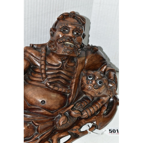 501 - AN ORIENTAL CARVED HARDWOOD FIGURE OF A RECLINING IMMORTAL WITH DRAGON, on a separate carved hardwoo... 