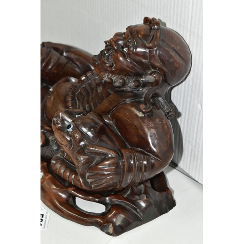 501 - AN ORIENTAL CARVED HARDWOOD FIGURE OF A RECLINING IMMORTAL WITH DRAGON, on a separate carved hardwoo... 