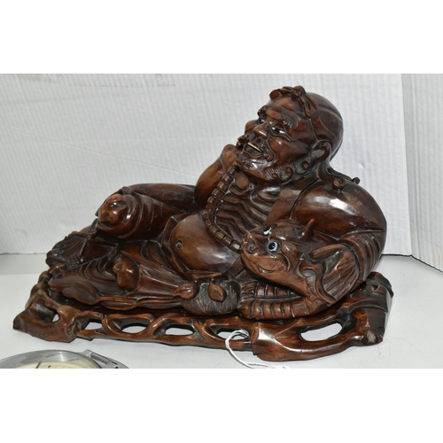 501 - AN ORIENTAL CARVED HARDWOOD FIGURE OF A RECLINING IMMORTAL WITH DRAGON, on a separate carved hardwoo... 