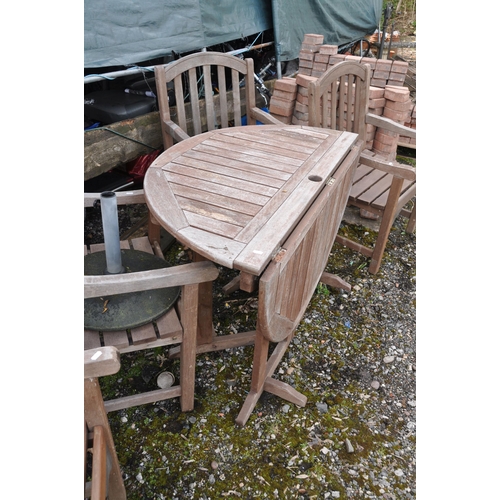 1005 - A CIRCULAR HARDWOOD GARDEN TABLE with four matching arm chairs, cushions  and a parasol base, table ... 