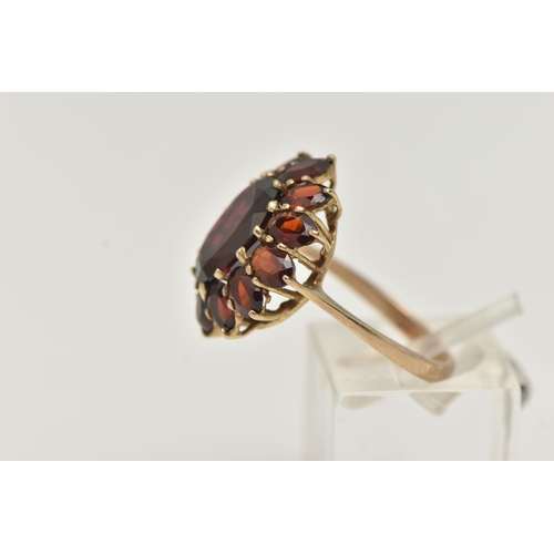 17 - A GARNET CLUSTER RING, designed as a central oval garnet within an oval garnet surround, in claw set... 