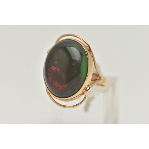 6 - A TREATED OPAL RING, the oval opal cabochon in a collet setting to the bifurcated shoulders and oute... 