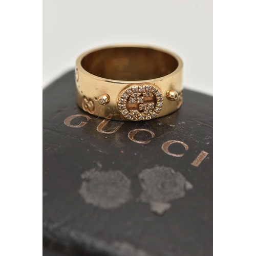 77 - AN 18CT GOLD 'GUCCI' ICON BAND RING, a wide yellow metal band with a repetitive 'Gucci' logo and a p... 