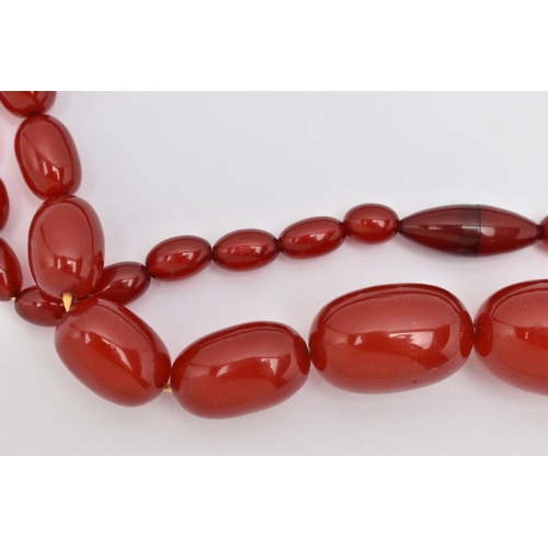 86 - A BAKELITE CHERRY AMBER BEAD NECKLACE, a single strand of oval beads, largest bead measures approxim... 