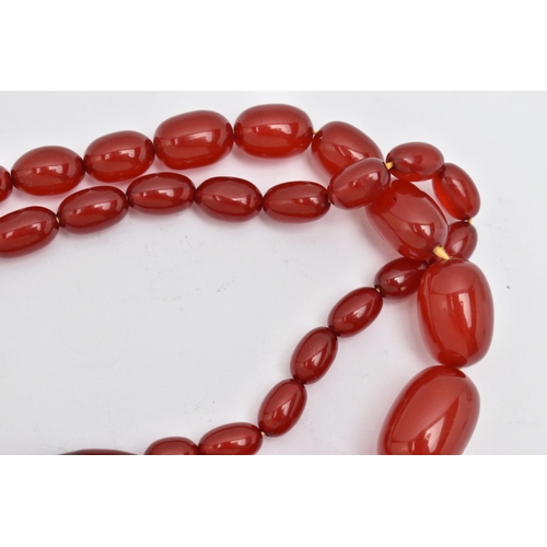 86 - A BAKELITE CHERRY AMBER BEAD NECKLACE, a single strand of oval beads, largest bead measures approxim... 