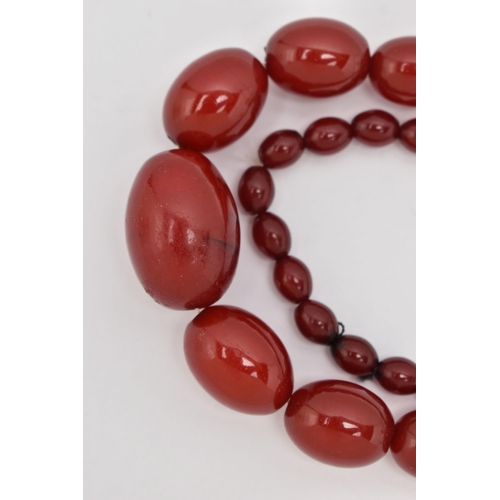 87 - A BAKELITE CHERRY AMBER BEAD NECKLACE, a single strand of oval beads, largest bead measures approxim... 