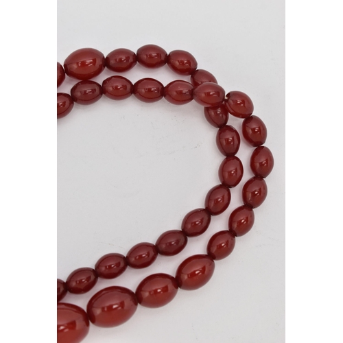 87 - A BAKELITE CHERRY AMBER BEAD NECKLACE, a single strand of oval beads, largest bead measures approxim... 