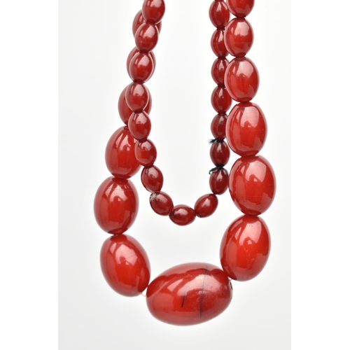 87 - A BAKELITE CHERRY AMBER BEAD NECKLACE, a single strand of oval beads, largest bead measures approxim... 