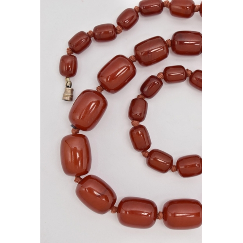 88 - A BAKELITE CHERRY AMBER BEAD NECKLACE, a single strand of rectangular oval beads, largest bead measu... 