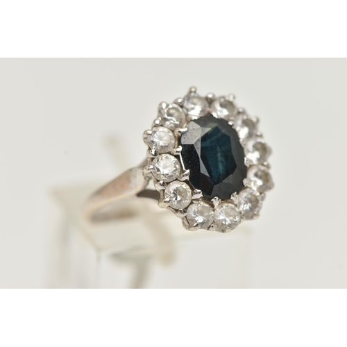 94 - A 9CT GOLD SAPPHIRE RING, a principally set oval cut sapphire, with a surround of circular cut cubic... 