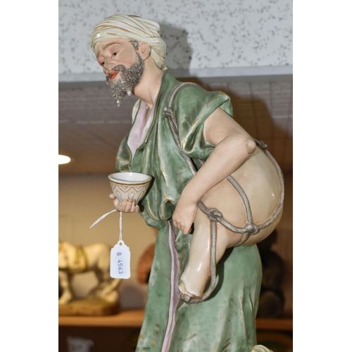 431 - A ROYAL DUX SCULPTURE OF A WATER CARRIER, the male figure carries an animal skin container across hi... 