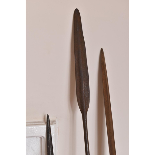 549 - THREE TRIBAL HUNTING SPEARS, the first features a wooden shaft and a grooved arrow shaped steel tip,... 