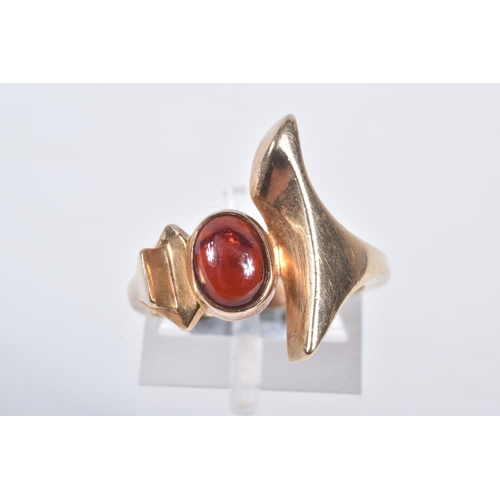 17 - A 9CT GOLD GARNET DRESS RING, abstract design set with an oval garnet cabochon, collet set between a... 