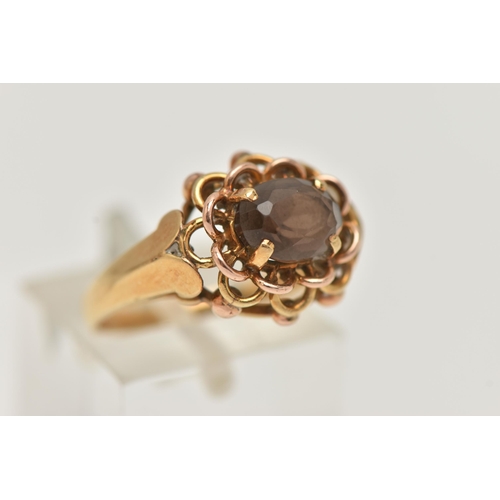 76 - A YELLOW METAL SMOKY QUARTZ RING, set with an oval cut smoky quartz, in a four claw open work settin... 