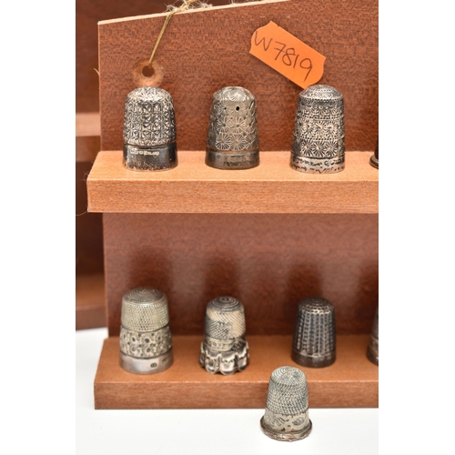 143 - A SELECTION OF SILVER THIMBLES AND TWO DISPLAY SHELVES, to include twenty-two thimbles, various desi... 