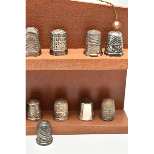 143 - A SELECTION OF SILVER THIMBLES AND TWO DISPLAY SHELVES, to include twenty-two thimbles, various desi... 