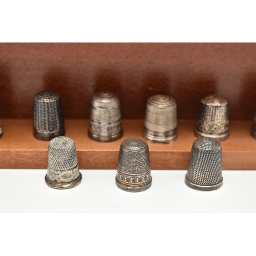 143 - A SELECTION OF SILVER THIMBLES AND TWO DISPLAY SHELVES, to include twenty-two thimbles, various desi... 