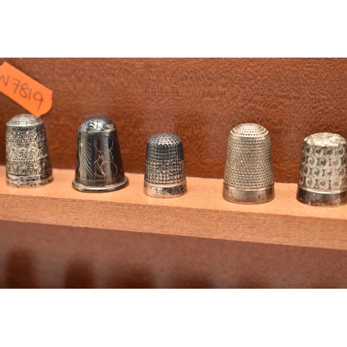 143 - A SELECTION OF SILVER THIMBLES AND TWO DISPLAY SHELVES, to include twenty-two thimbles, various desi... 