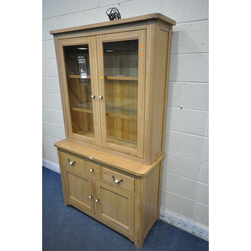 1262 - A MODERN LIGHT OAK BOOKCASE, the double glazed doors enclosing two glass shelves, atop a base fitted... 