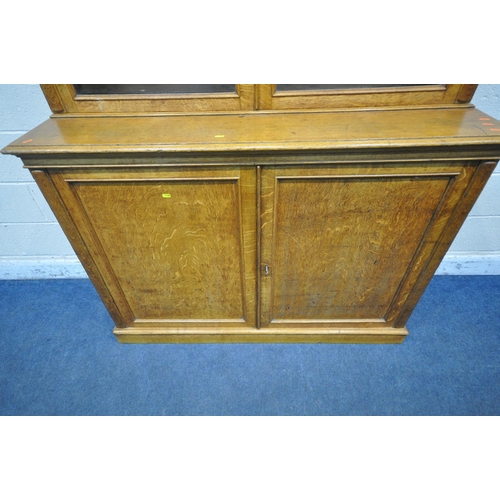 1300 - AN EARLY 20TH CENTURY OAK BOOKCASE, the double glass doors enclosing four adjustable shelves, atop a... 