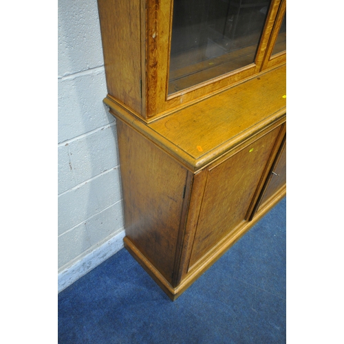 1300 - AN EARLY 20TH CENTURY OAK BOOKCASE, the double glass doors enclosing four adjustable shelves, atop a... 