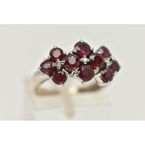 19 - A WHITE METAL RUBY AND DIAMOND DRESS RING, set with ten circular cut rubies, each claw set, with thr... 