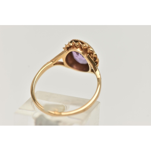 21 - A 9CT GOLD AMETHYST RING, centering on an oval cut amethyst, collet set with a fine rope twist surro... 