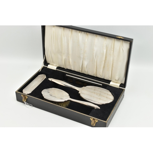 115 - A CASED FOUR PIECE SILVER VANITY SET, to include a hair brush, hand held mirror, clothes brush and a... 