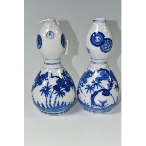 582 - A PAIR OF JAPANESE DOUBLE GOURD VASES, painted in blue with trees and foliage, unmarked, height appr... 