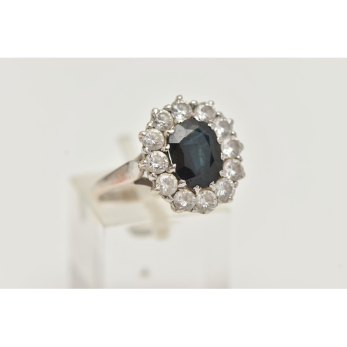 156 - A 9CT GOLD SAPPHIRE RING, a principally set oval cut sapphire, with a surround of circular cut cubic... 