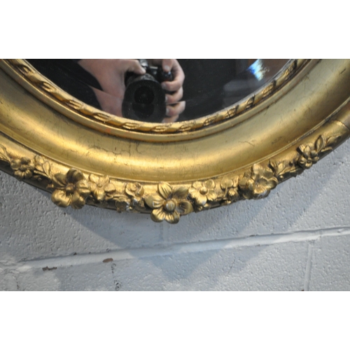 1202 - A 19TH CENTURY GILT WOOD OVAL WALL MIRROR, with floral carvings and a later bevelled edge plate, 66c... 