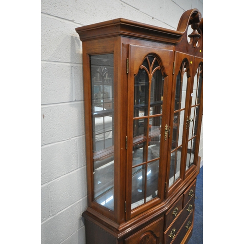 1209 - A LATE 20TH CENTURY HARDWOOD BOOKCASE, the twin swan neck pediment, flanking a finial, four glazed d... 