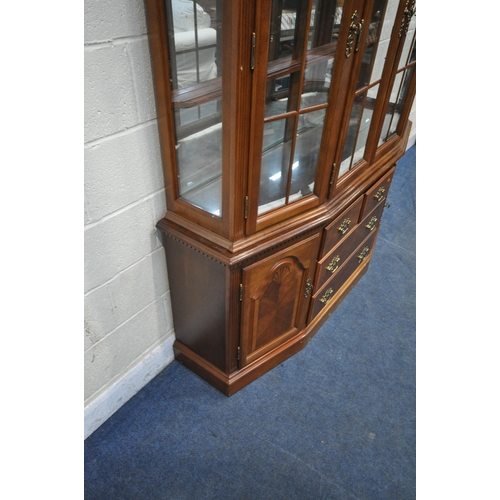 1209 - A LATE 20TH CENTURY HARDWOOD BOOKCASE, the twin swan neck pediment, flanking a finial, four glazed d... 