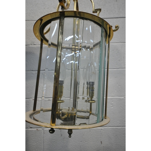 1220 - A 20TH CENTURY BRASS CYLINDRICAL HALL LANTERN, the glass panes encasing a four branch light fitting,... 