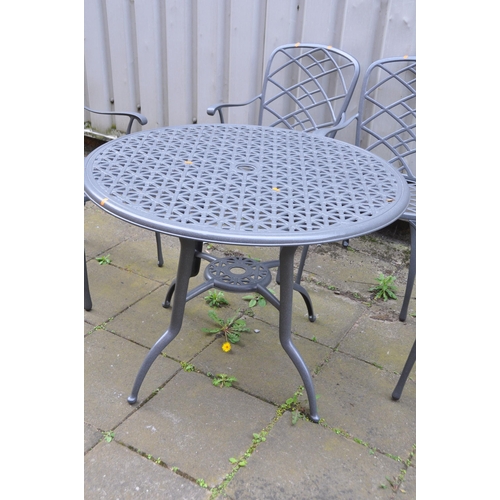 1012 - A GREY PAINTED ALUMINIUM GARDEN SET comprising of a 100cm diameter round table with pierced linear d... 