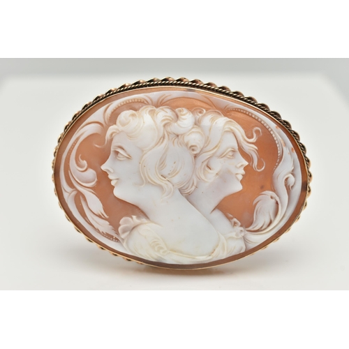 11 - A LARGE YELLOW METAL CAMEO BROOCH, of an oval form, carved shell cameo depicting two ladies in profi... 