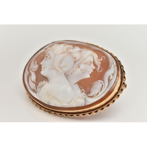 11 - A LARGE YELLOW METAL CAMEO BROOCH, of an oval form, carved shell cameo depicting two ladies in profi... 