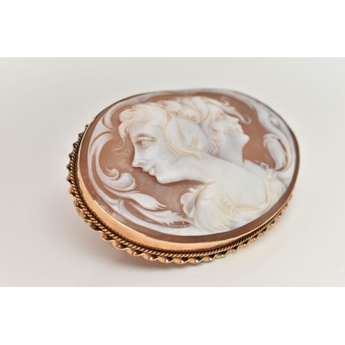 11 - A LARGE YELLOW METAL CAMEO BROOCH, of an oval form, carved shell cameo depicting two ladies in profi... 