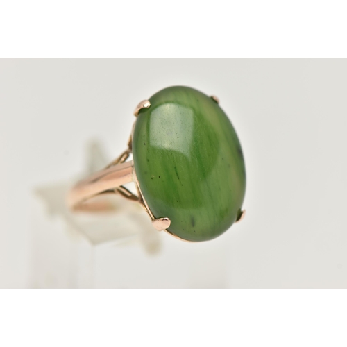 14 - A YELLOW METAL, NEPHRITE CABOCHON RING, of an oval form, nephrite measuring approximately length 18.... 