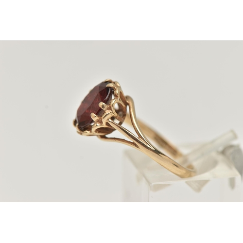 16 - A 9CT GOLD GARNET SET RING, oval cut garnet in a double four claw setting, measuring approximately 1... 