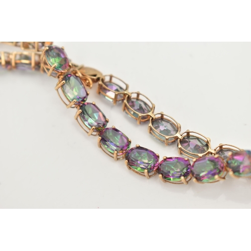 20 - A 9CT GOLD MYSTIC TOPAZ LINE BRACELET, designed as a series of twenty-two oval cut, mystic coated to... 