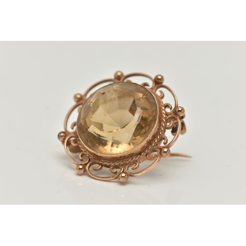 23 - A 9CT GOLD CITRINE BROOCH, of a circular form, set with a large circular cut citrine, milgrain colle... 