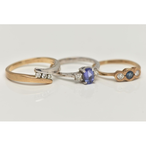 47 - THREE 9CT GOLD GEM SET RINGS, the first a three stone diamond ring in a bi colour bypass mount, hall... 