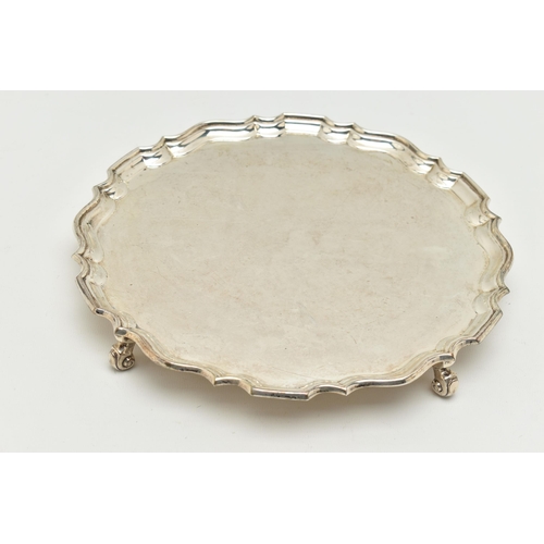 173 - A GEORGE V SILVER SALVER, a circular form salver with a fluted border, raised on four scrolled feet,... 